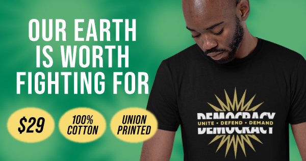 A Black person with a beard looks down while wearing a black “Democracy: Unite, Defend, Demand” shirt. Our Earth Is Worth Fighting For: shirt is $29, 100% cotton, union printed.