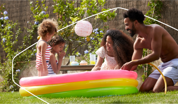 Family with two children happily playing in an inflatable swimming pool outdoors.